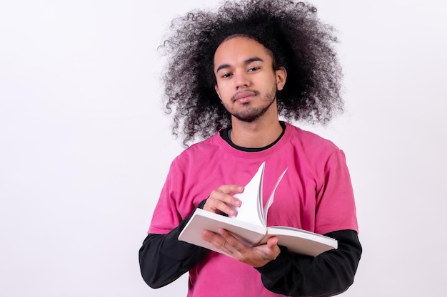 Pink tshirt reading and turning the pages Young man with afro hair on white background