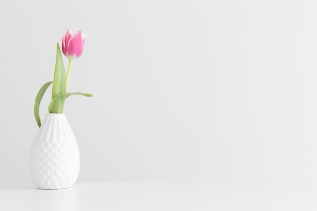 Pink tulip in a vase on a white table with blank copy space