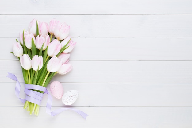 Pink tulip on the white surface. Easter surface.