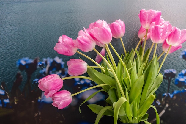 Pink tulips bouquet in vase on sea background