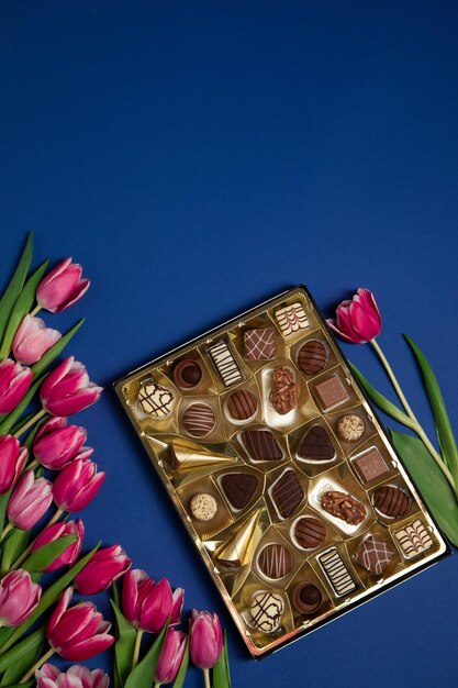 Pink tulips and box of chokolates on a blue background