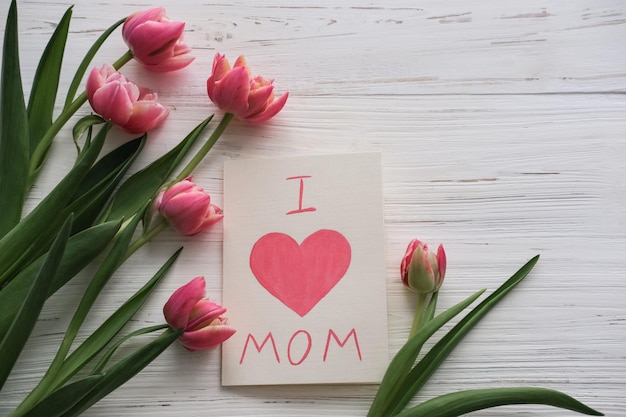 Pink tulips and a card with the text I love mom on a white background