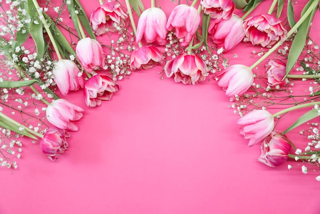 Pink tulips and white gypsophila flowers bouquet on a pink background Mothers Day birthday celebration concept Copy space for text Mockup