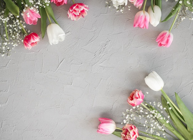 Pink tulips and white gypsophila flowers bouquet on a stylish gray stone background Mothers Day birthday celebration concept Copy space for text