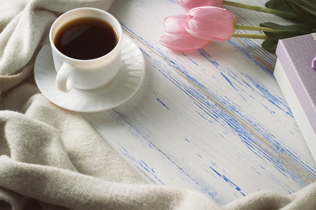 Pink Tulips, White Scarf, Coffee Cup and Gift Box on a White Wooden surface