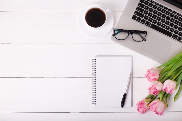 Pink tulips with a festive mood and coffee on white wooden boards.