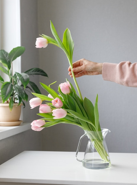 Pink tulips with green leaves in a glass vase