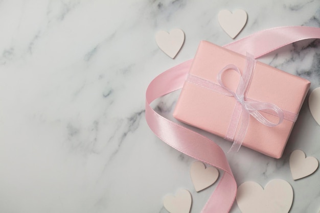 Pink valentine gift with white hearts on a marble background