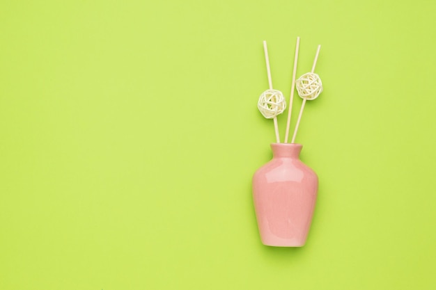 Pink vase with dry sticks on a green background