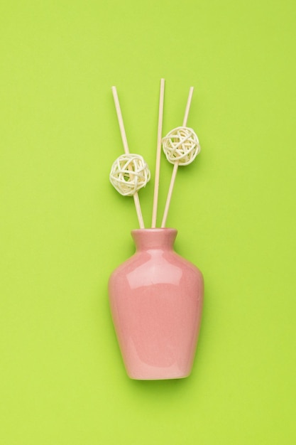 Pink vase with incense sticks on a green background