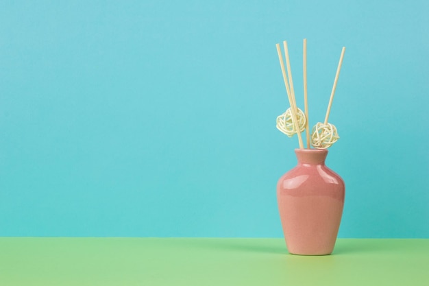 Pink vase with incense sticks on a greenblue background