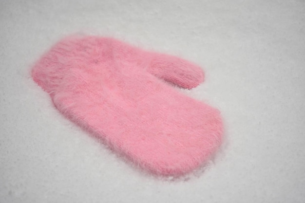 A pink warm mitten lies on the snow