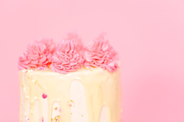 Photo pink and white buttercream cream cake with pink sprinkles and white chocolate ganache drip.