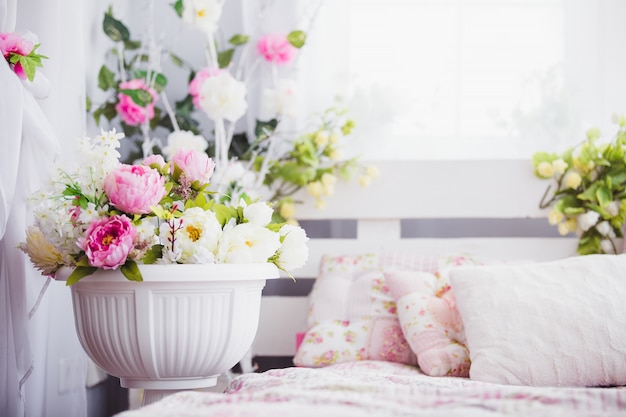 Pink and white flowers in a vase near the bed