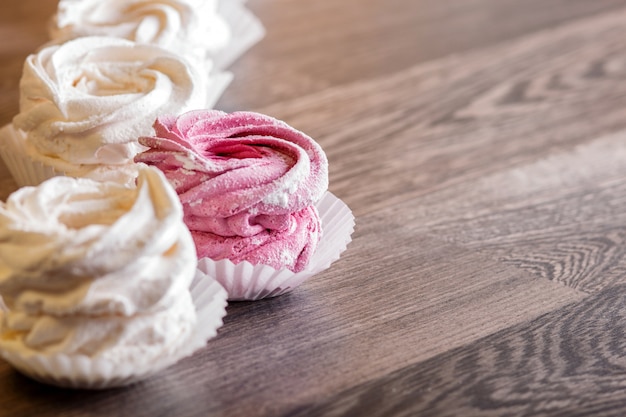 Pink and white homemade marshmallows on a gray wooden background.