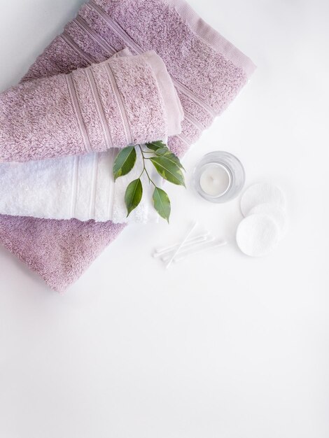 Pink and white towels with cotton pads and ear sticks on the white background