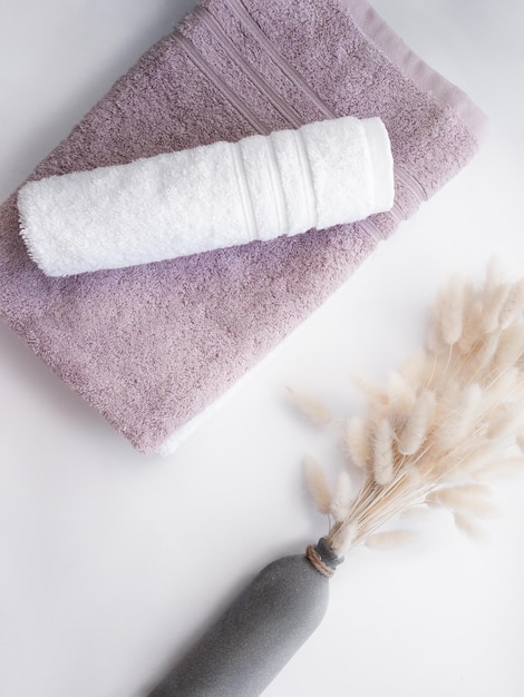 Pink and white twisted towel with dried flowers on the white background