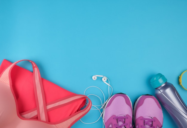 Pink women's sneakers, bottle of water, clothes and bras for sports