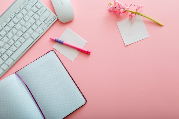 Pink work desk. Work space Office table with computer keyboard and mouse notepad stationery. Top view office table desk with copy space on pink background. Flat lay