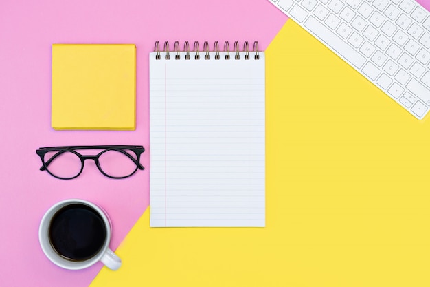 Pink and yellow colorful workspace with a notepad and glasses