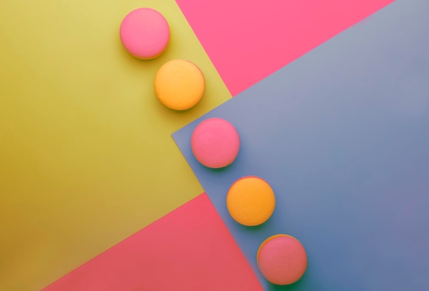 Pink yellow macaroons on yellow blue pink graphic background neon color place for text creative layout top view