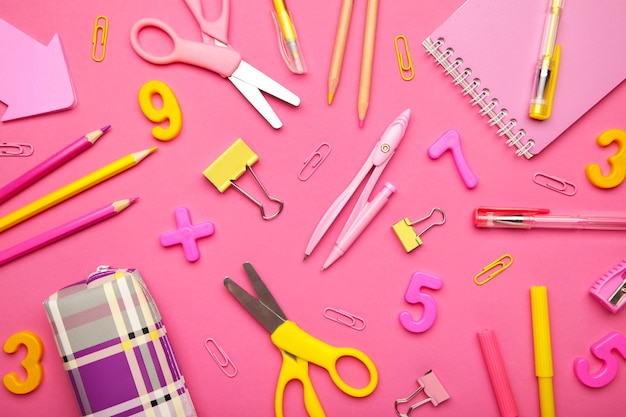 Pink and yellow school supplies on pink background. Back to school concept.