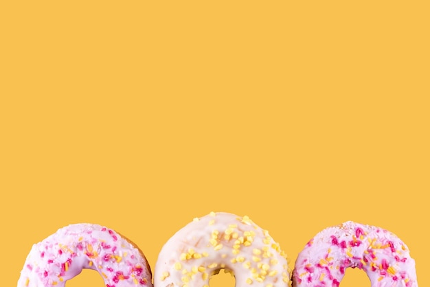 Pink and yellow spricled donuts on a yellow background Space for text highquality photos