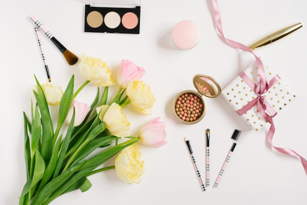 Pink and yellow tulip flowers accessories and cosmetics The layout of a female desktop in a home office Flat lay top view