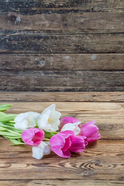 Pink and yellow tulip flowers on rustic wooden background