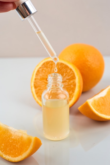 Pipette with orange essential oil over bottle and oranges. Natural medicine concept. Aromatherapy