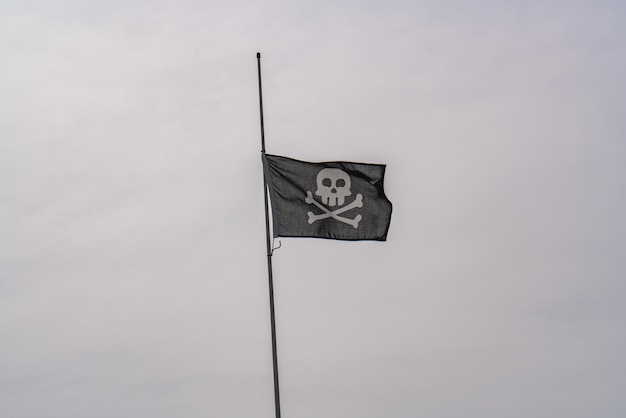 Pirate flag waving in the gray sky skull and crossbones