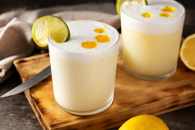 Pisco sour cocktail on wooden table. Traditional peruvian cocktail