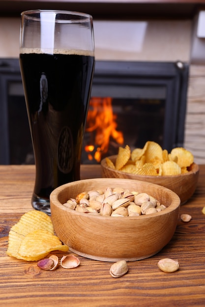 Pistachio, chips and beer on a background of a burning fireplace