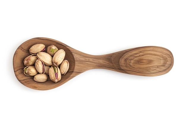 pistachio nuts with shell in the wooden spoon isolated on the white background top view