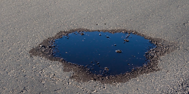 The pit filled with water serves as a reminder of the road's need for repair