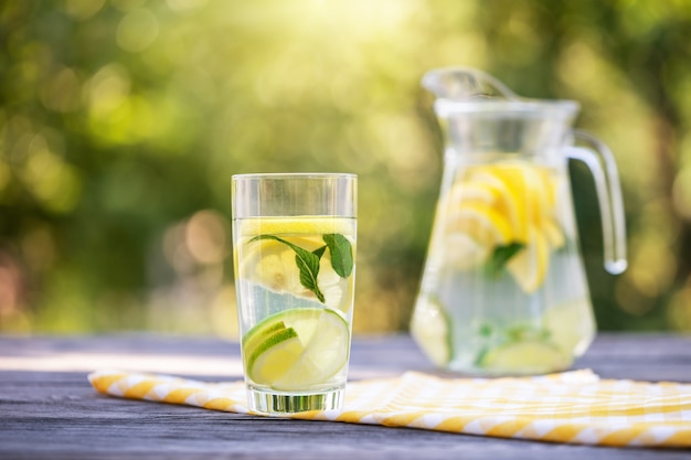 Pitcher and glass of homemade lemonade on wooden table