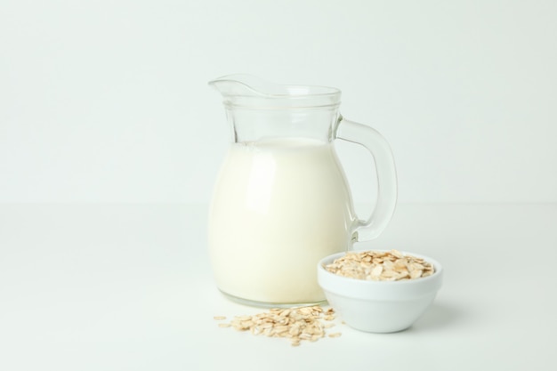 Pitcher of milk and cereals on white background