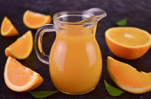 A pitcher of orange juice next to a half of oranges.