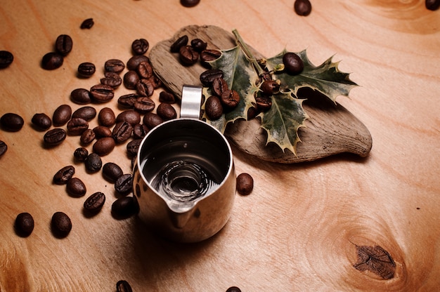 Pitcher with water among fresh coffee beans and dried plants