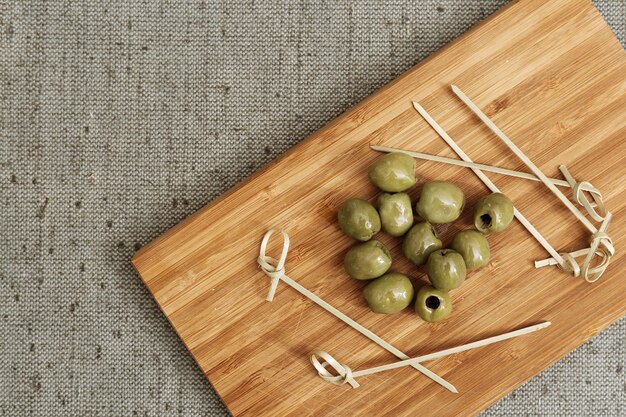 Pitted and marinated green olives on wooden board. 