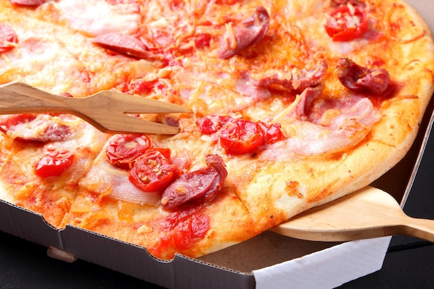 Pizza on black wooden background Italian pizza with tomatoes sausages and cheese on dark background Italian cuisine Copy space