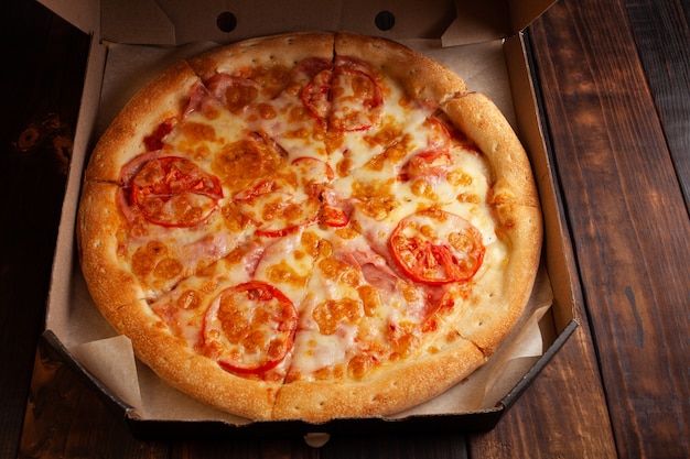 Pizza in a box on a wooden table