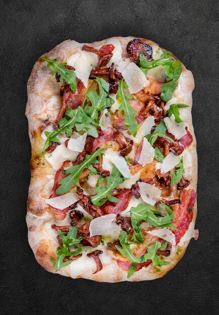 Pizza Carbonara with bacon chanterelles arugula mozzarella parmesan pesto Roman pizza rectangular on dark background