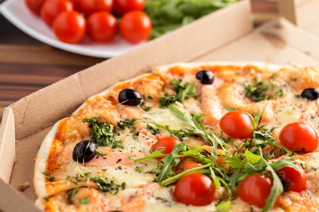 Pizza in cardboard box on a table close up