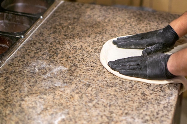 Pizza chef kneads pizza dough in gloves