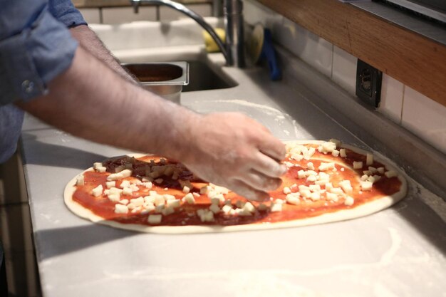 Pizza chef put sauce on base in a commercial kitchen