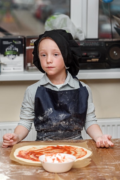 Pizza children and the concept of cooking children make pizza Preparation of pizza a master class for children and a fuzzy focus on ingredients for pizza