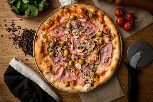 Pizza and cooking ingredients on wooden table