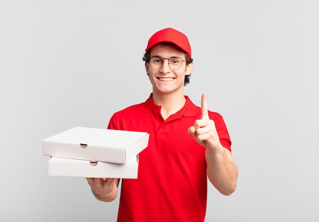 Pizza deliver boy smiling proudly and confidently making number one pose triumphantly, feeling like a leader