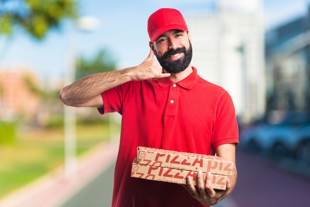 Pizza delivery man making phone gesture on unfocused background